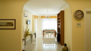 A dining area with a chandelier, a clock, and a vase with plants. - Guest House Train Station (Mestre)