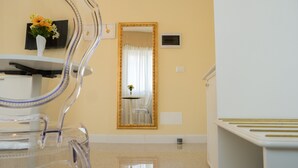 A hotel room with a large mirror, a small table with a vase, and a white cabinet. - Guest House Train Station (Mestre)