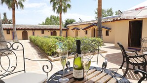 A patio with a table set for two, featuring a bottle of wine and two glasses.