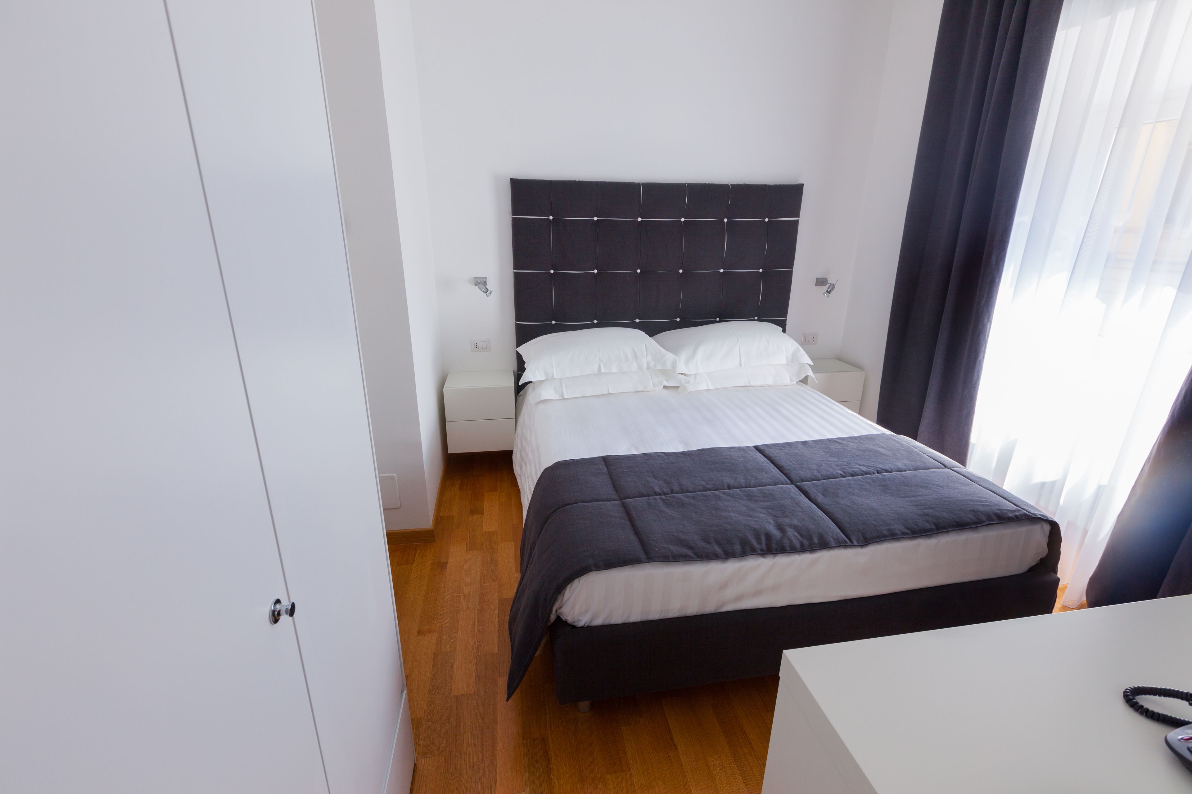 Ein ordentlich eingerichtetes Hotelzimmer mit Bett, Nachttischen und einem Kleiderschrank.