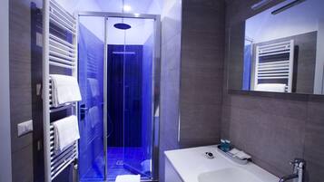 Ein modernes Badezimmer mit einer begehbaren Glasdusche, einer weißen Badewanne und einem Handtuchhalter.