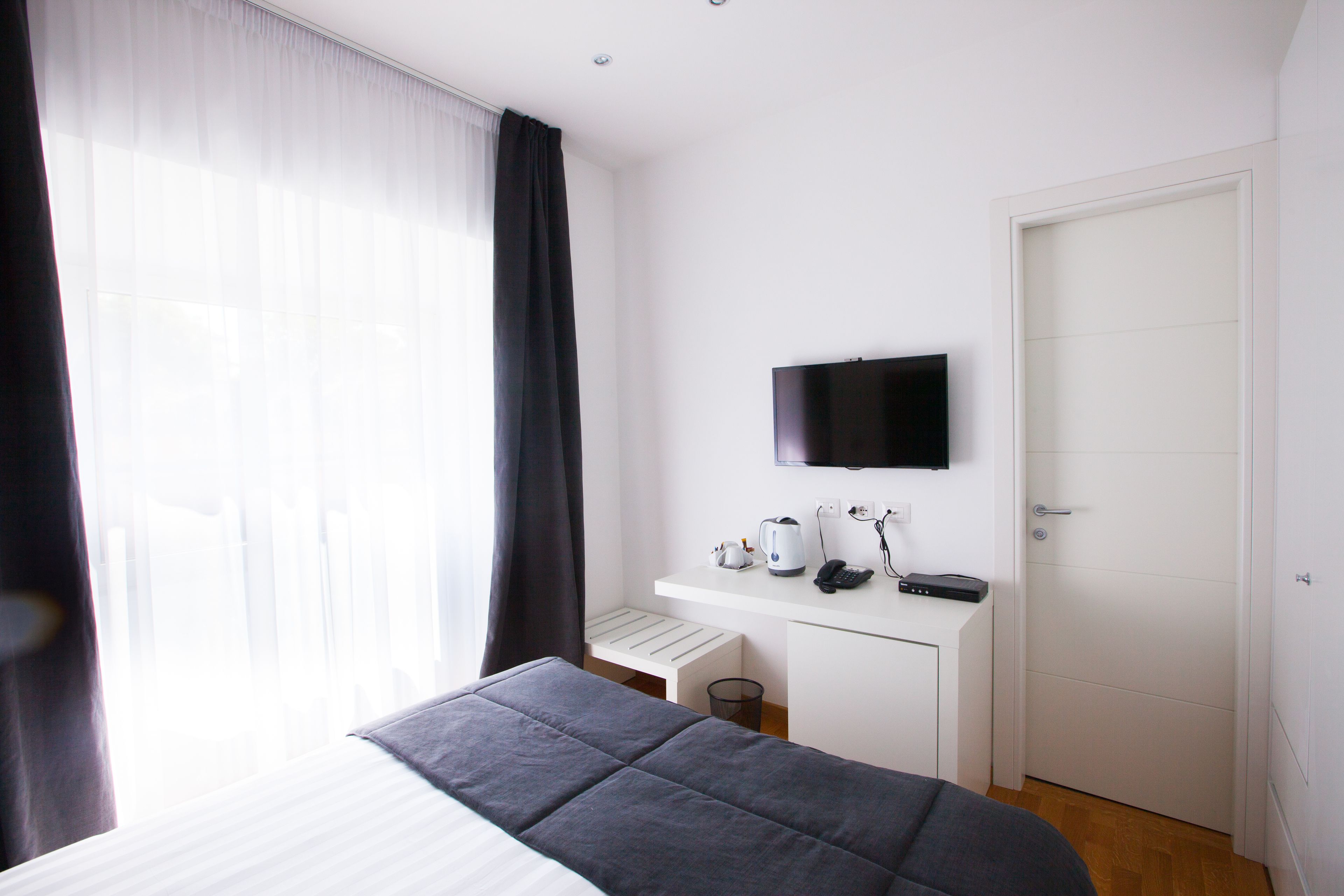 Une chambre d’hôtel équipée d’un lit, d’un bureau avec un téléviseur à écran plat, d’une bouilloire, d’une machine à café et d’un téléphone.