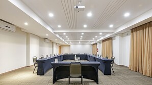 A conference room with a long table, chairs, a projector, and an air conditioning unit.
