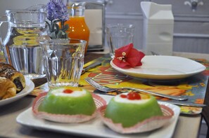 A breakfast table with a pitcher of orange juice, a glass of water, and a plate with a red flower. - Stupor Mundi Bed and Breakfast (Palermo)