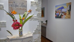 A room with a white wall, a stone accent wall, a wooden sign, and a painting. - Stupor Mundi Bed and Breakfast (Palermo)