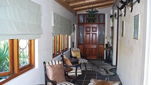 A cozy lounge area with striped chairs, a wooden table, and a zebra rug. - Kingna Lodge (Montagu)