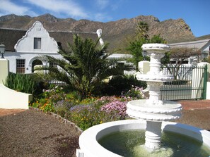 A white building with a fountain and a mountain in the background. - Kingna Lodge (Montagu)