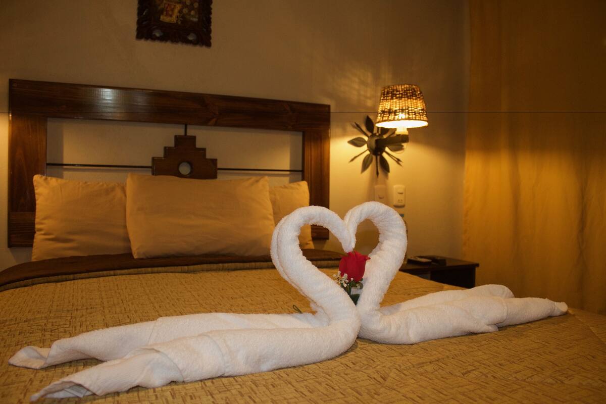 Una habitación de hotel con cama, mesita de noche y lámpara de pared.