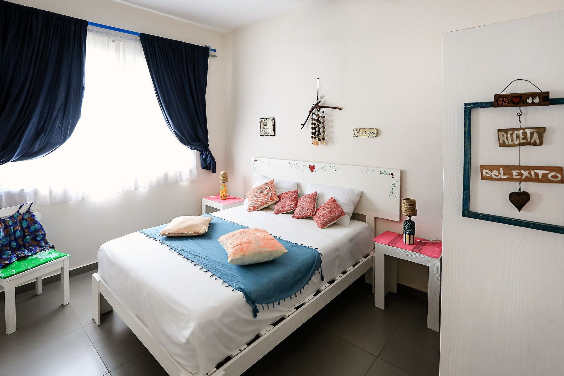 A neatly arranged bedroom with a bed, bedside tables, and a wall with decorative items.