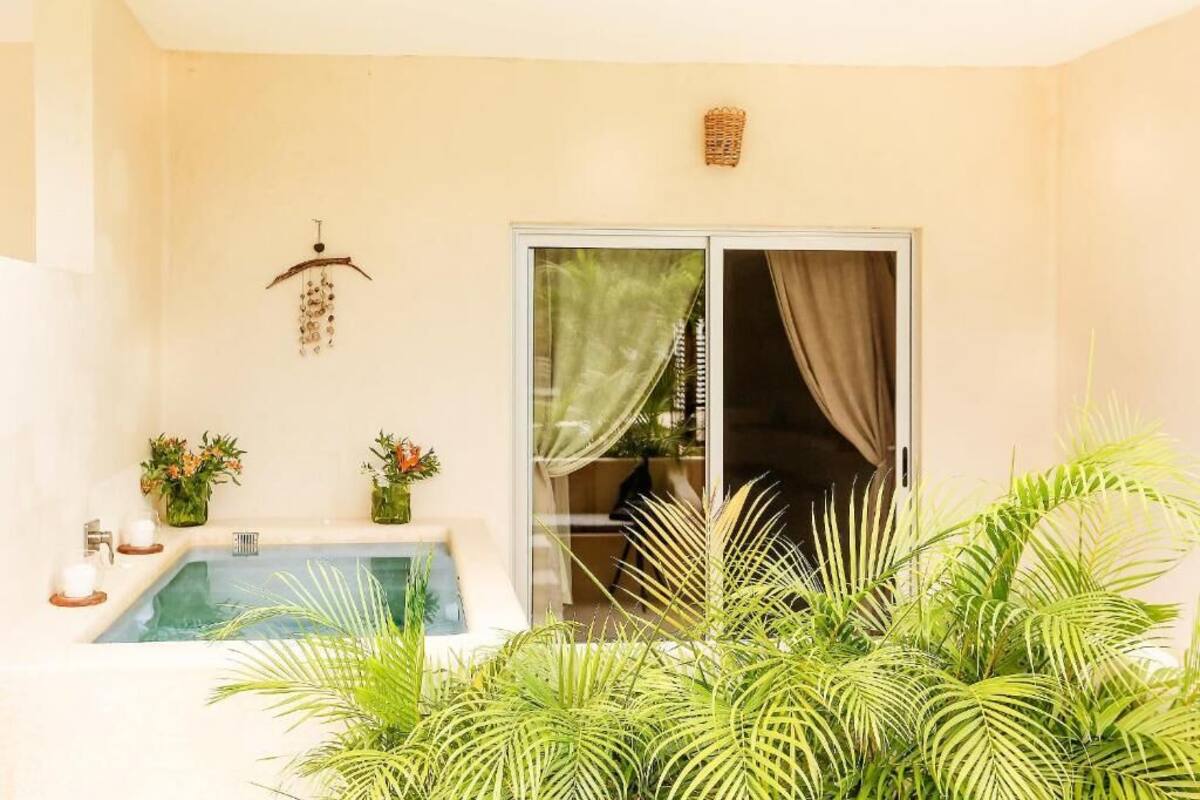 A spa area with a hot tub, two flower arrangements, and a sliding glass door leading to a covered outdoor area.