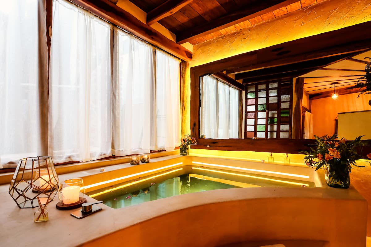 A spa room with a soaking tub, candles, and a decorative vase.