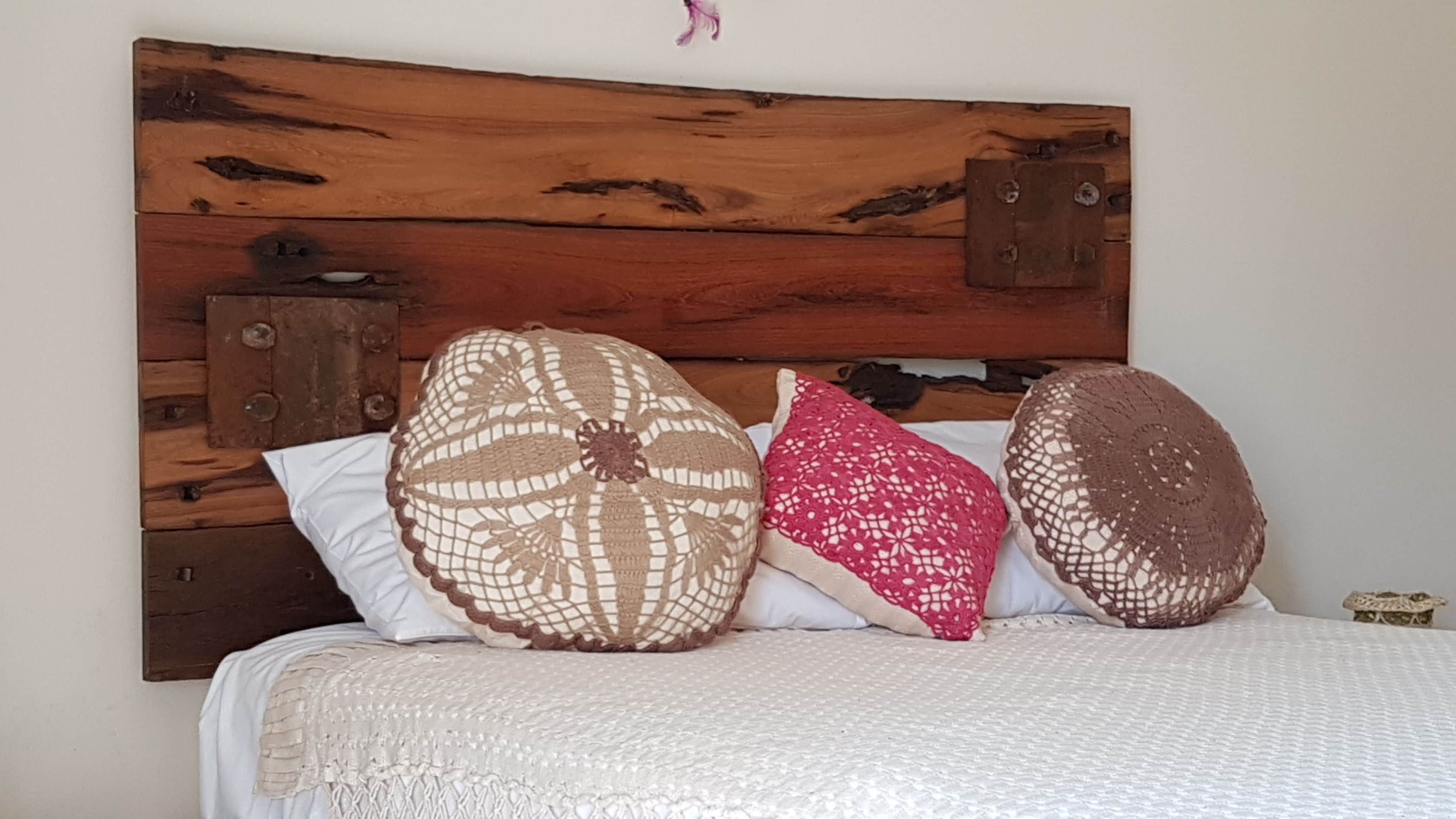 A bed with a wooden headboard, three pillows, and a white blanket.