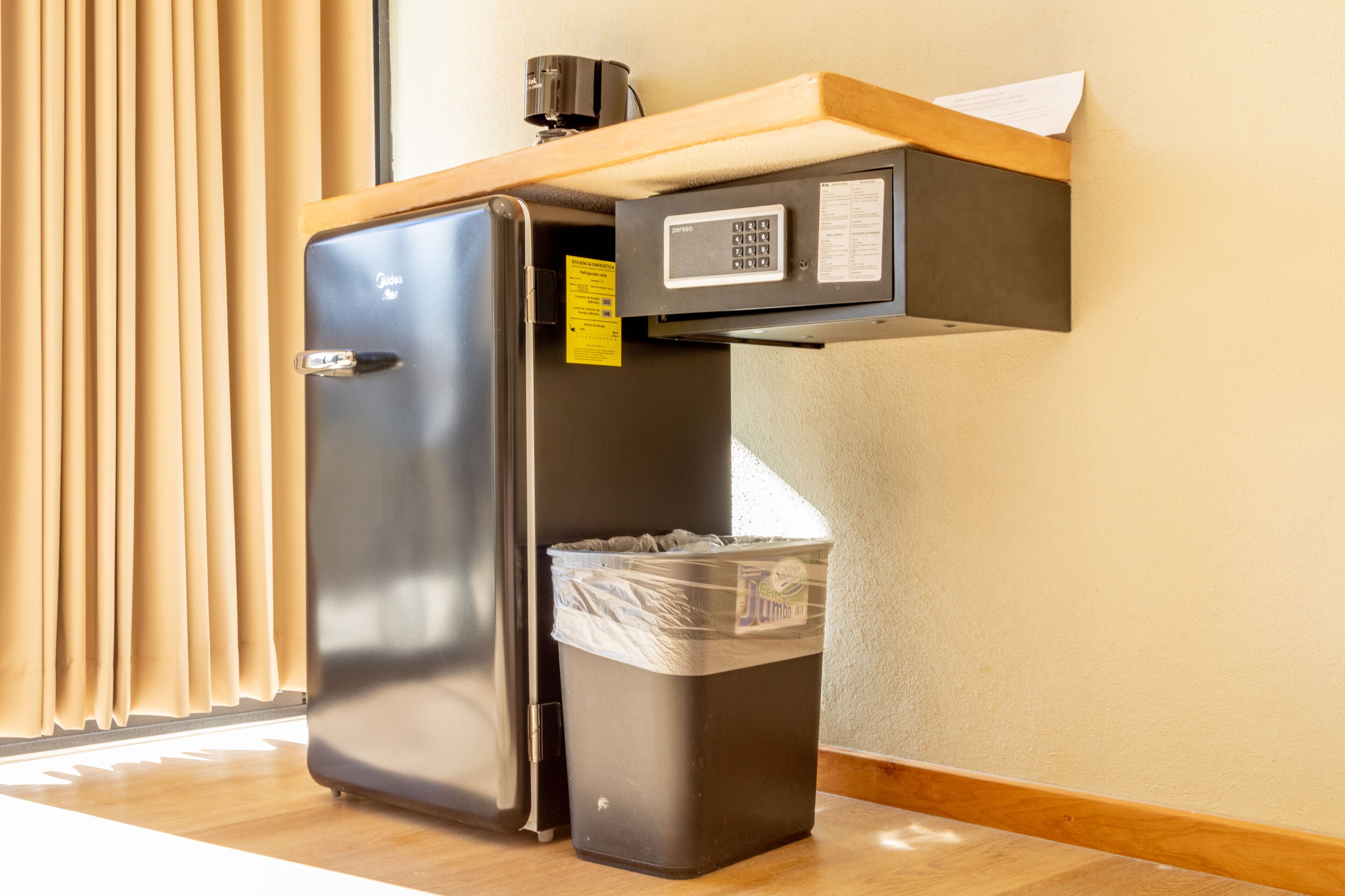 A compact kitchenette with a refrigerator, a trash bin, and a microwave.