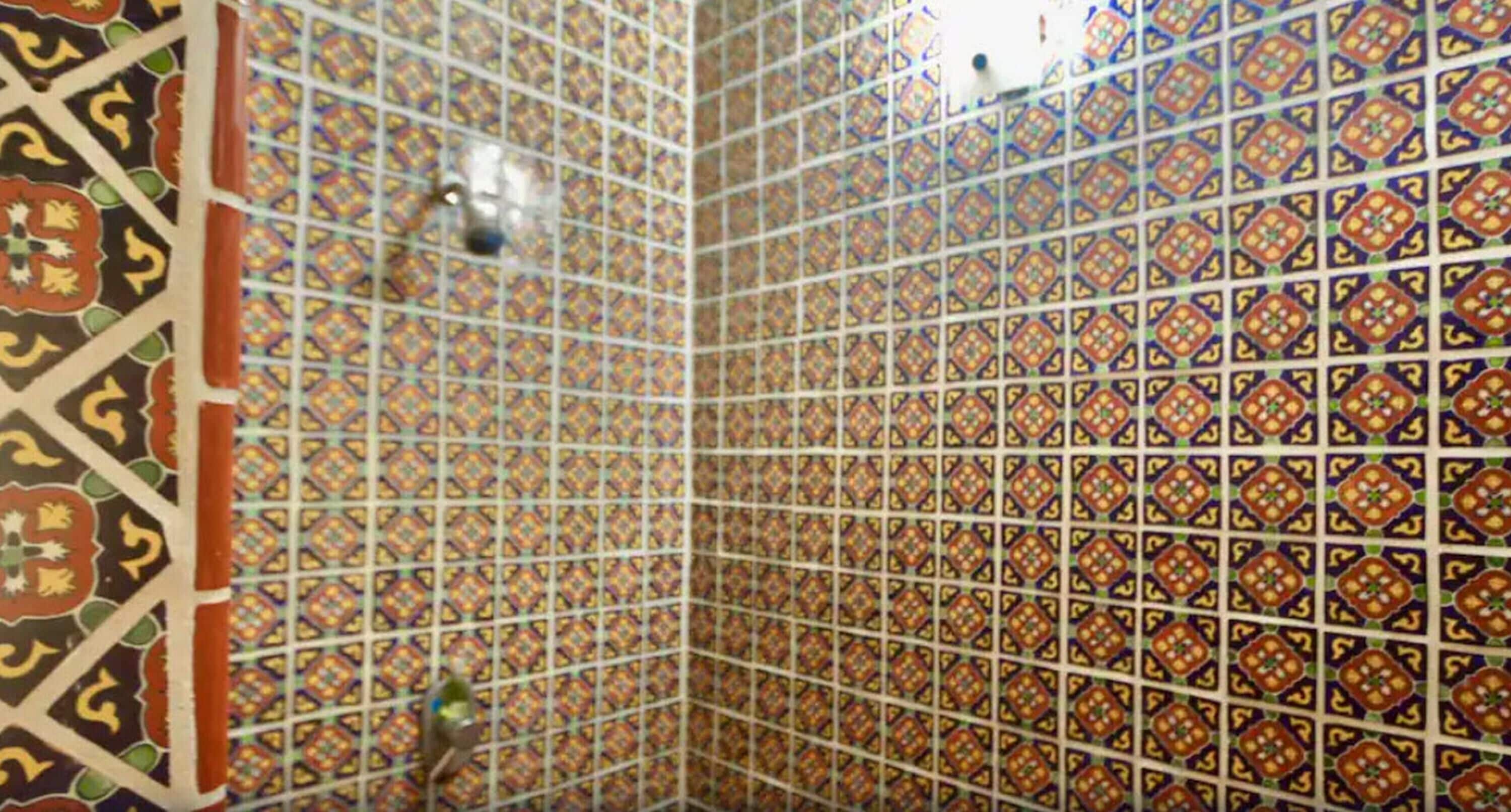 Quarto com paredes de azulejos estampados e um canto com moldura decorativa.