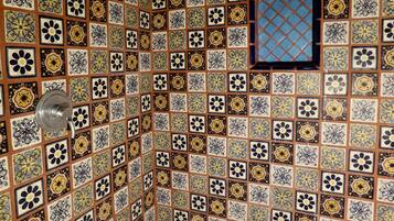 A tiled wall with a geometric pattern and a small arched window.