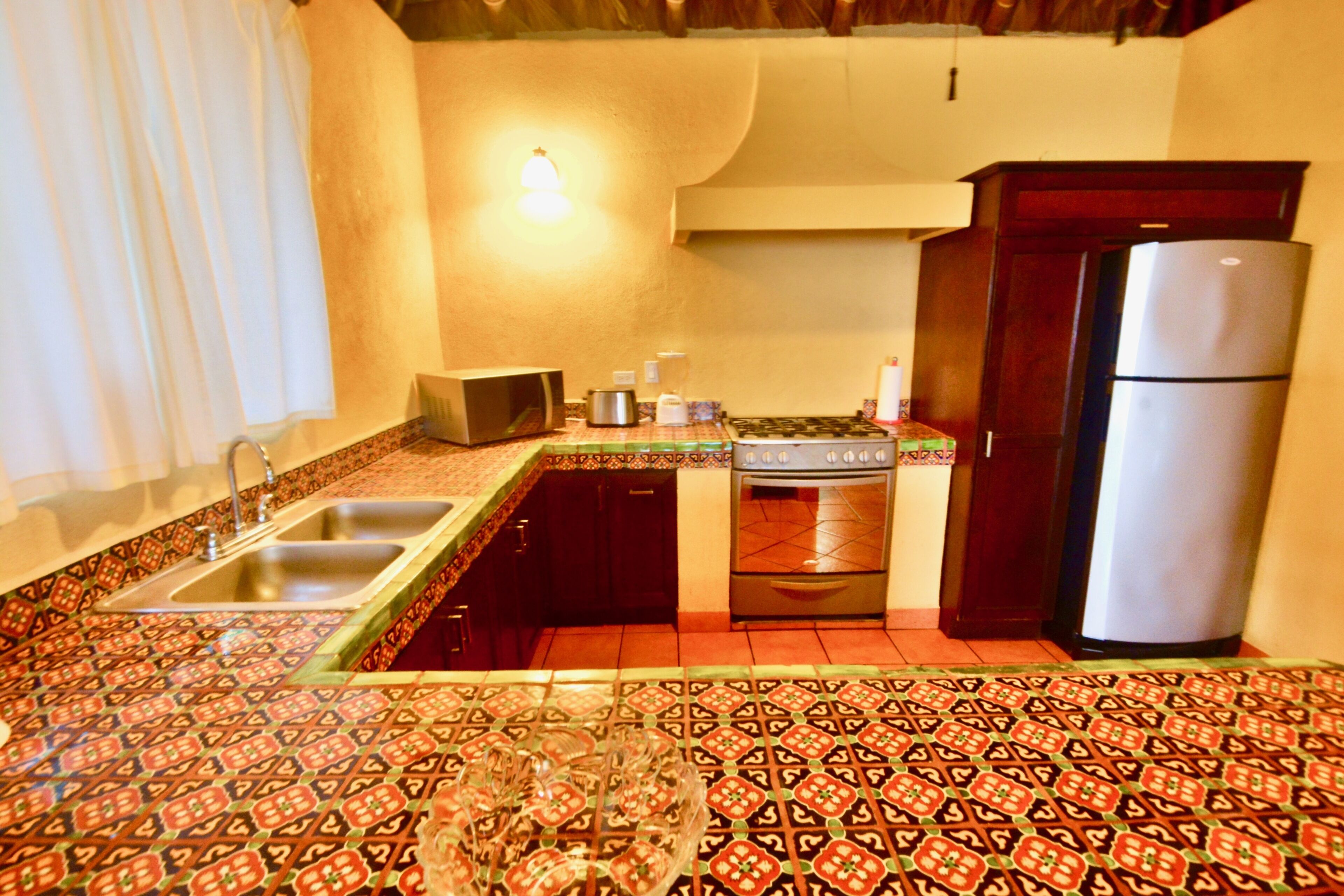 A kitchen with a patterned tile floor, a refrigerator, a stove, and a sink.