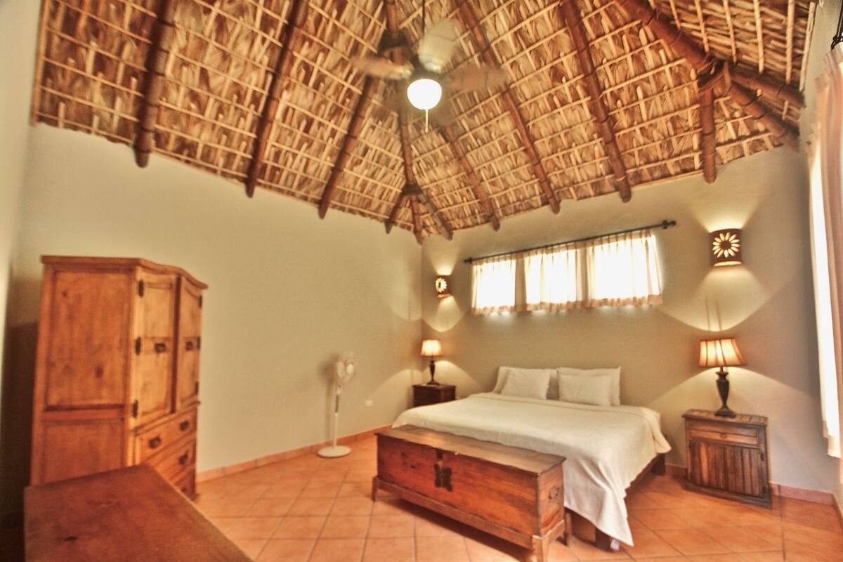 Une chambre à coucher avec un plafond en bois, un lit, des lampes de chevet, une table de chevet et une armoire.