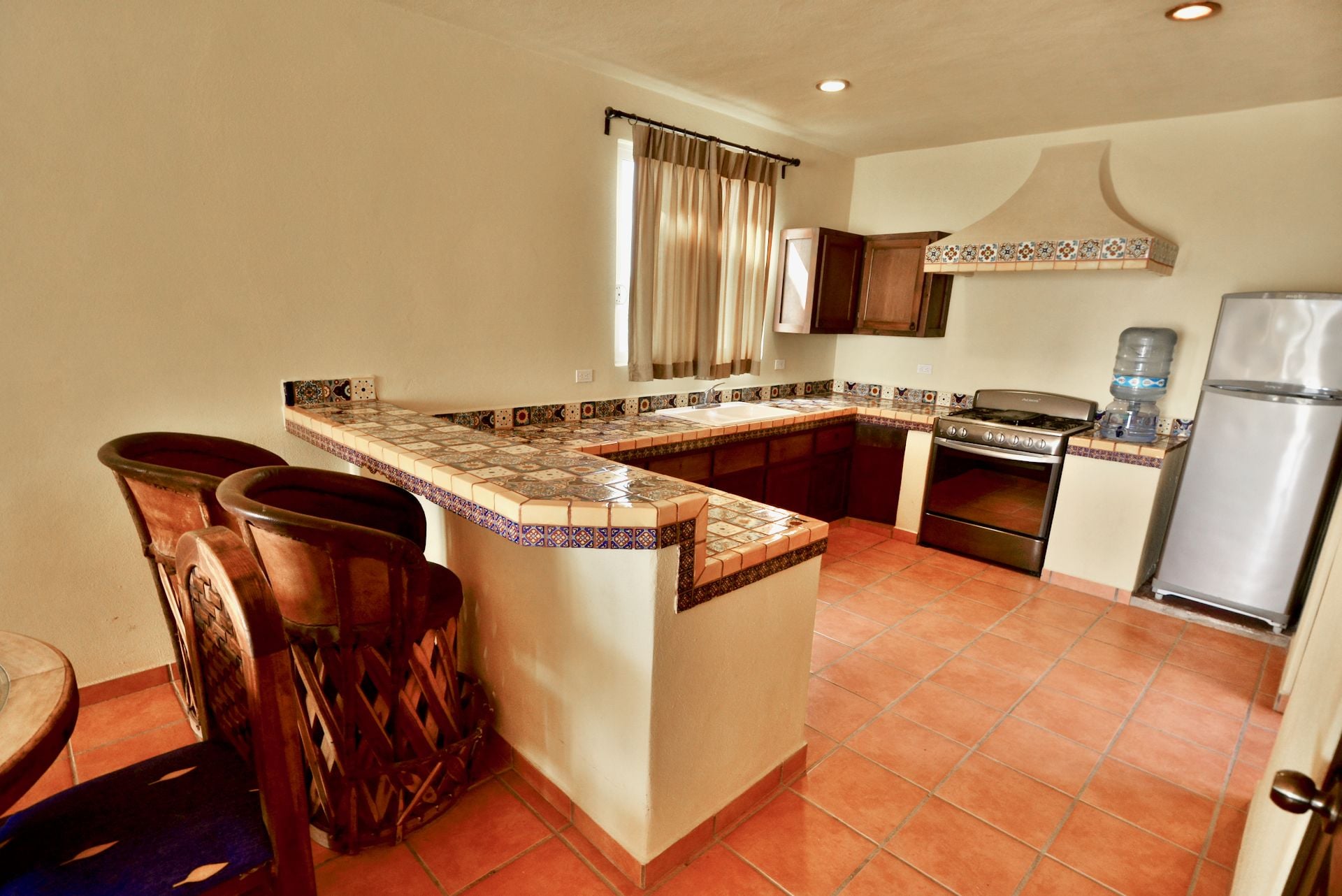 A kitchen with a tiled backsplash, a stove, a sink, and a refrigerator.