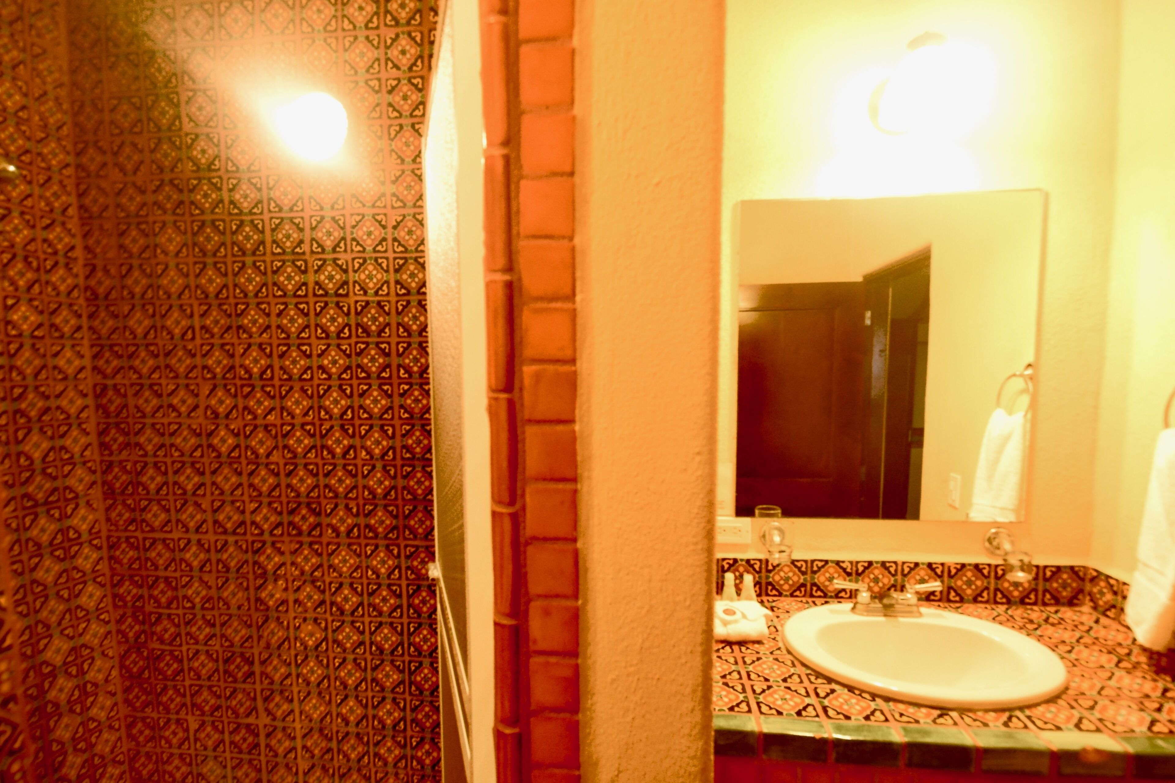 Une salle de bain avec des carreaux décorés, un lavabo et un miroir.