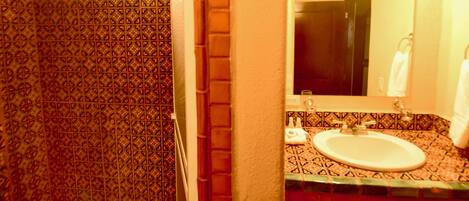 A bathroom with patterned tiles, a sink, and a mirror.