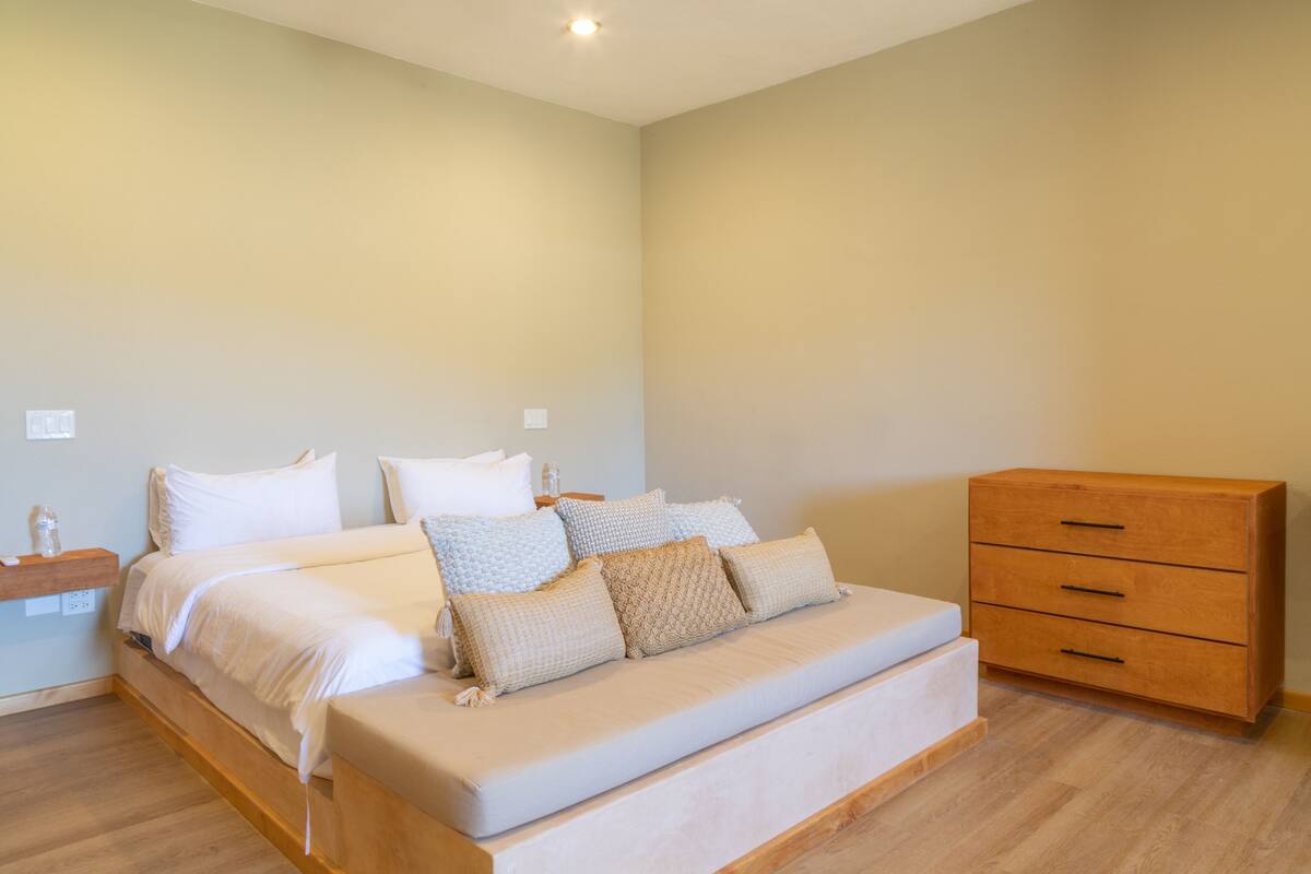 Une chambre à coucher avec un lit, des tables de chevet et une commode en bois.