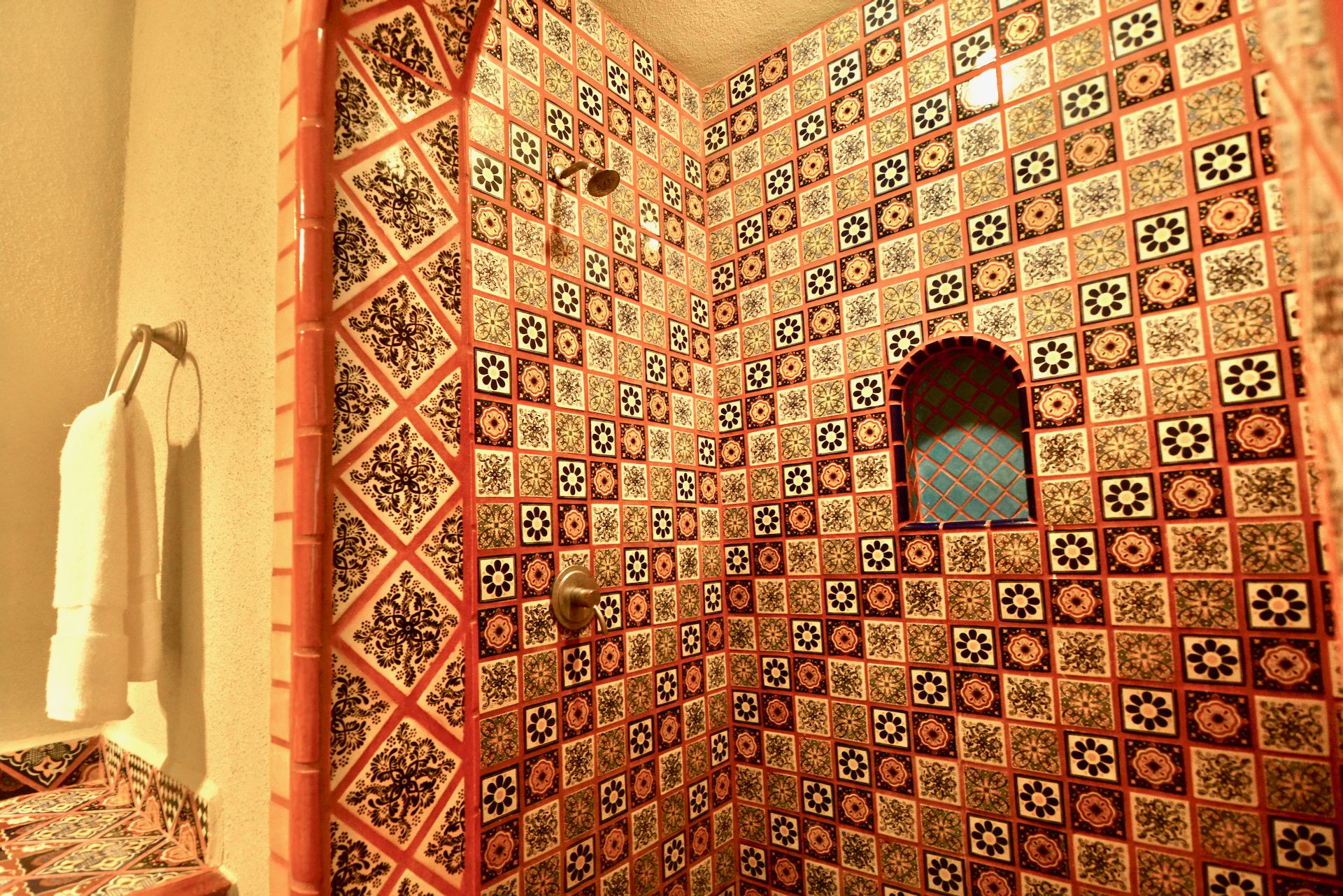 Un baño con pared de azulejos que presenta un diseño geométrico y un pequeño ventanal de arco.