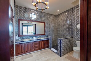 A bathroom with patterned tiles, a wooden vanity, a large mirror, and a toilet.