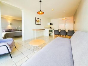 A modern living room with a sofa, a dining table with chairs, a bed, and a kitchenette. - Balcon del Alferez (Xalapa)