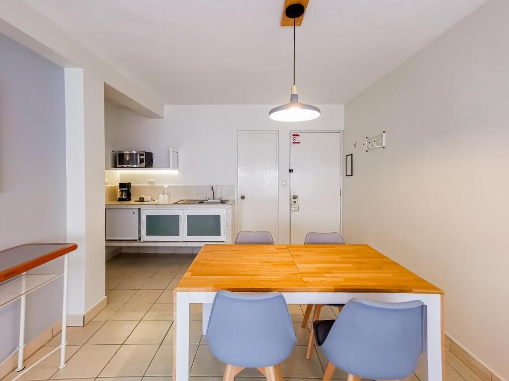 Una cocina compacta con una mesa y sillas, microondas y cafetera.