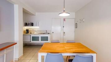 Una cocina compacta con una mesa y sillas, microondas y cafetera.