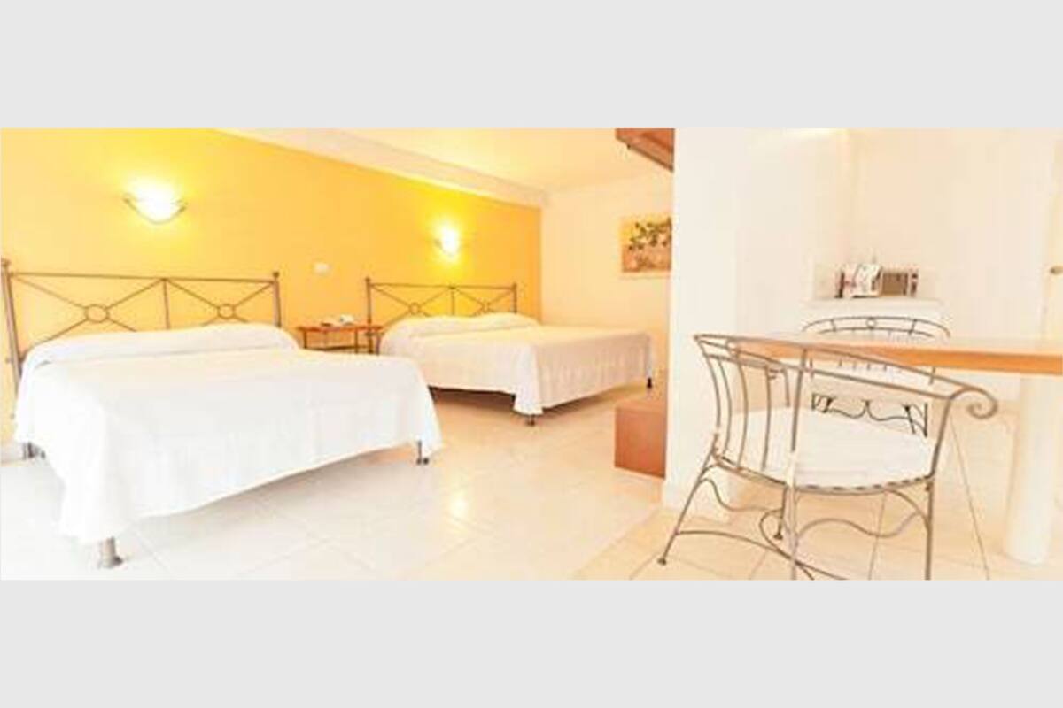 A hotel room with two beds, a desk, and a chair.