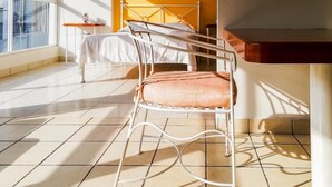 Una habitación iluminada por el sol, con una cama, una silla y una mesita.