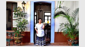 Una mujer de pie en un umbral, con una planta a la izquierda y otra a la derecha.