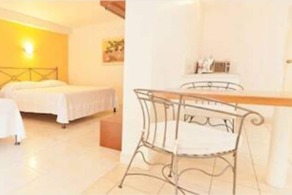A hotel room with two beds, a small table, and a chair.