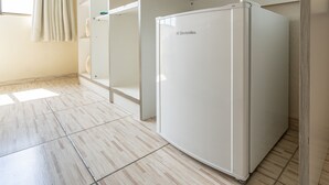 Una habitación con un refrigerador blanco, un mueble de madera y piso de baldosas.