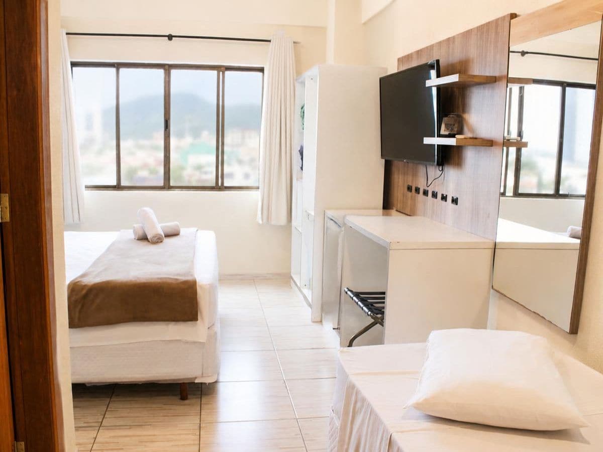 A hotel room with a bed, a desk, a TV, and a window with a view.