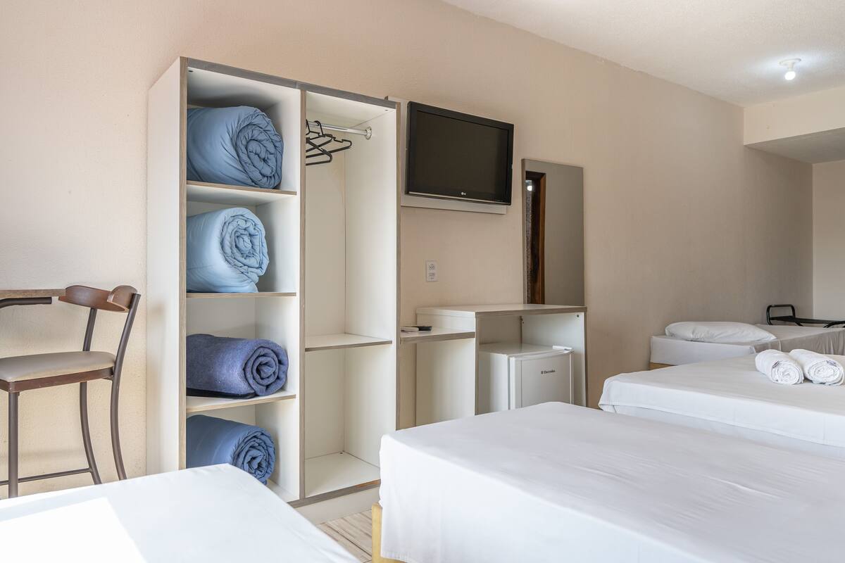 A hotel room with two beds, a TV, a wardrobe, and a desk.