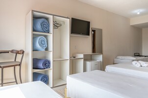Una habitación de hotel con dos camas, televisión, armario y escritorio.