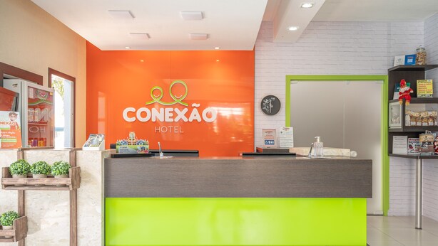 Un mostrador de recepción de hotel con una pared de color naranja brillante y un detalle en verde.
