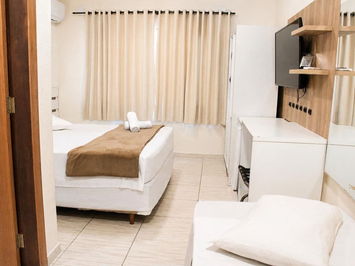 A hotel room with a bed, a desk, a television, and a wardrobe.