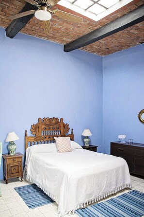 A bedroom with a wooden bed, two bedside tables, a ceiling fan, and a skylight. - Hotel Casa Carmen (San Miguel de Allende)