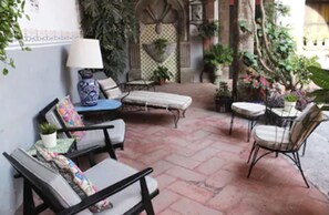 A patio area with outdoor seating, including a sofa and chairs, surrounded by potted plants and a decorative wall. - Hotel Casa Carmen (San Miguel de Allende)
