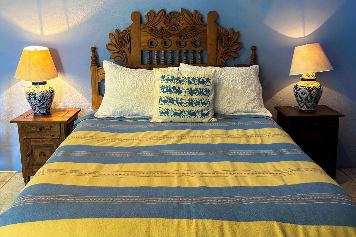 A bed with a striped bedspread, two nightstands with lamps, and a decorative headboard.