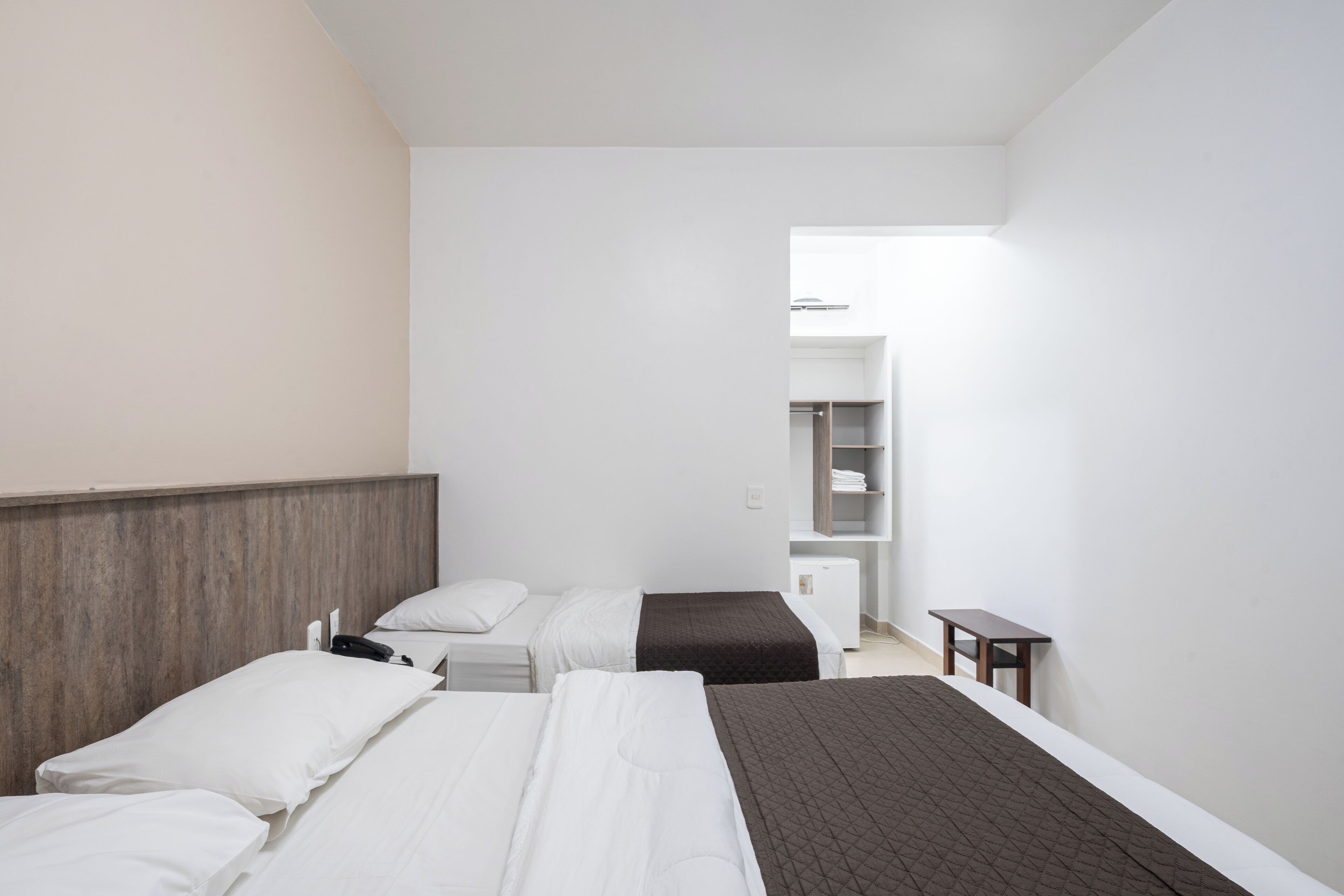 Une chambre d’hôtel avec deux lits, une tête de lit en bois, une table de chevet et une petite table.