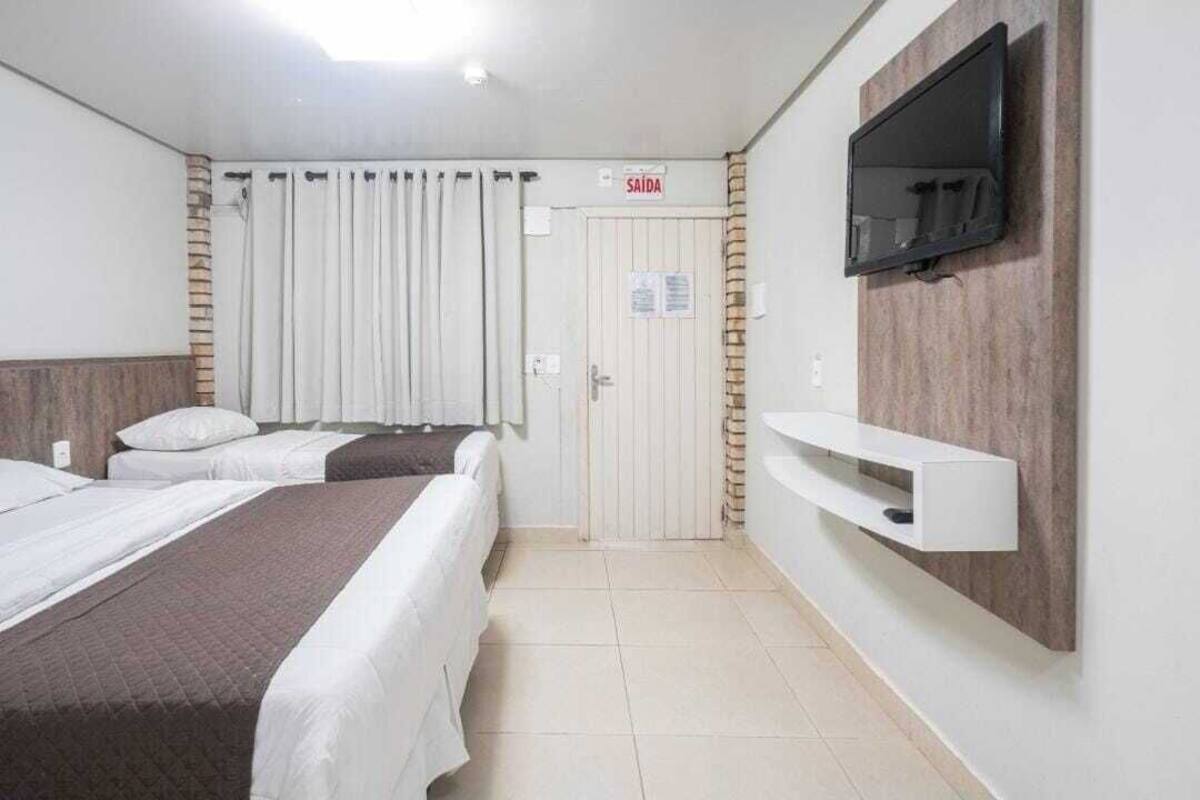 A hotel room with two beds, a TV mounted on the wall, and a sign indicating the exit.