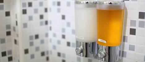 Un baño con pared de azulejos y dos dispensadores, uno para champú y otro para acondicionador.