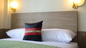 A neatly made bed with white and black pillows, a green-striped bedspread, and a wooden headboard.