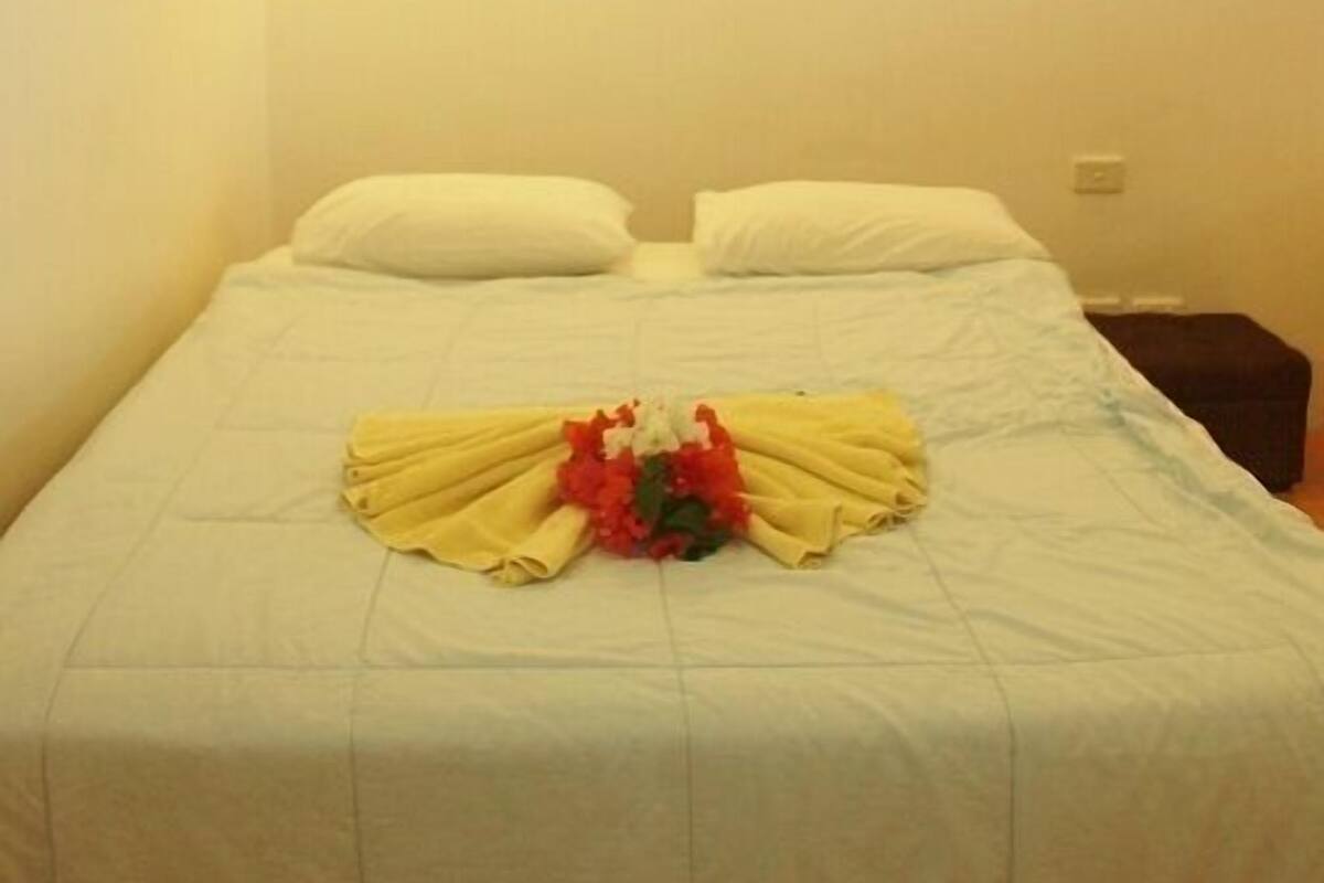 Een enkel bed met witte lakens en een bloemstuk in het midden.