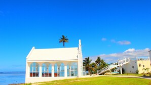 A white building with large windows and a staircase leading to a balcony. - Coral Lagoon Fiji Resort (Korolevu)