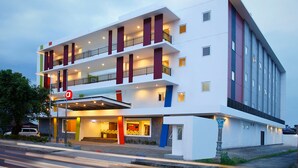 Ein mehrstöckiges Hotel mit modernem Design, mit Balkonen und einem überdachten Eingang.